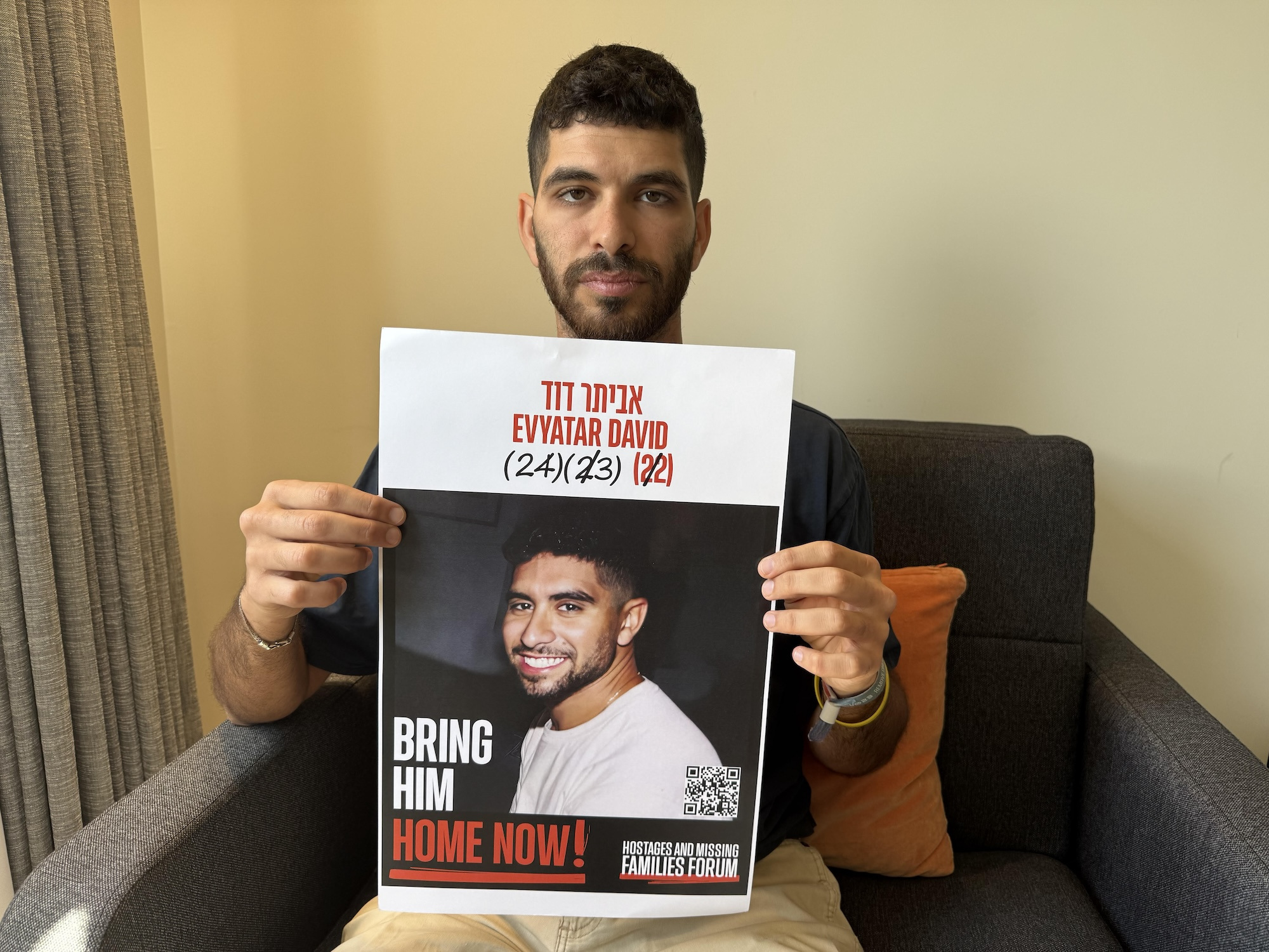 Ilay David holds a poster showing his brother, Evyatar, who was taken hostage by Hamas during the Oct. 7, 2023, attacks.