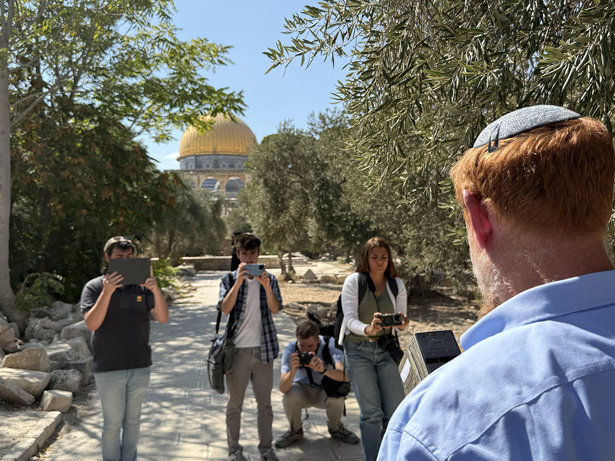 Rabbi Yehuda Glick reads prayers on the Temple Mount, with the Islamic Dome of the Rock in the background.