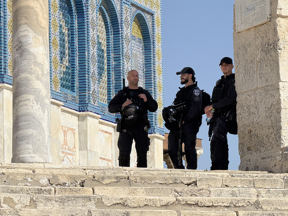 Three Israeli police officers at the top of the steps leading to the Islamic Dome of the Rock. The officers provide protection for Jewish and Christian pilgrims, prevent them from ascending the steps, and prevent Muslim visitors from interacting with them.