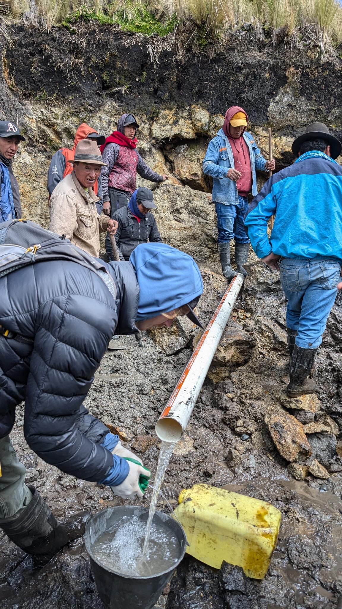 Quichua men help shovel dirt over newly laid water pipes in Balda Upaxi, Ecuador.